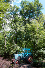 Blue tractor resting in forest on John's Hill, Budapest.