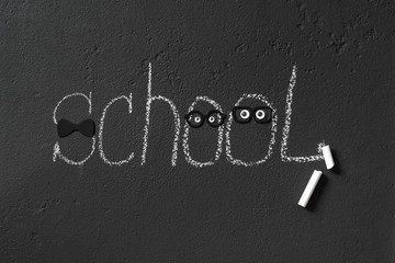 Word  “school” on the black chalkboard and drawn funny characters with glasses