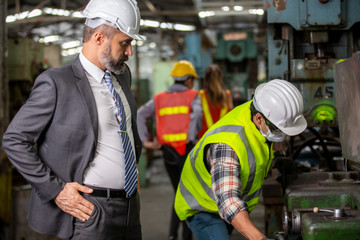 Business director and Mechanic engineer checking and discussing at factory shop floor.