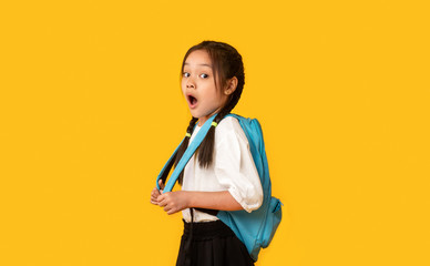 Shocked Asian Schoolgirl Looking At Camera Posing Over Yellow Background
