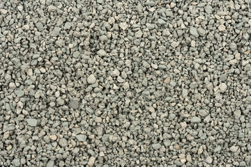 Gray small rocks ground texture. black small road stone background. gravel pebbles stone seamless texture. dark background of crushed granite gravel, close up. clumping clay