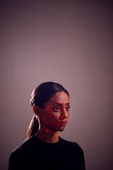 Facial Recognition Technology Concept As Woman Has Red Grid Projected Onto Face In Studio