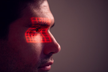 Facial Recognition Technology Concept As Man Has Red Grid Projected Onto Eye In Studio