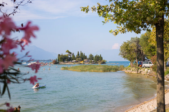 San Biagio Island distant view from San Biagio campground, with trees and flowers framing. manerba del Garda, Lombardy, Italy.