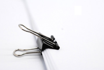 White paper clip and paper on white background.