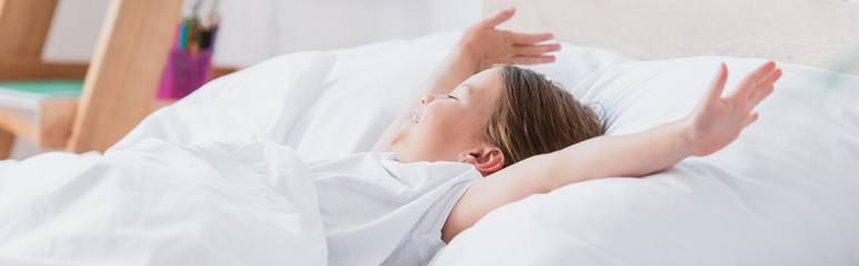 Fototapeta na wymiar horizontal image of awakened girl stretching while lying in bed