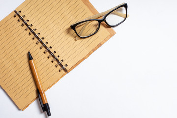 Fototapeta premium Top view of open notebook with pen or pencil and glasses isolated on white background. Flat lay, copy space