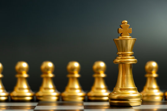 Gold king chess piece stand in front of pawn on black background (Concept of leadership, management)