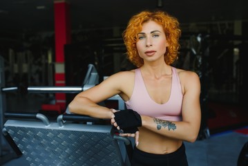 Fototapeta na wymiar portrait of a sporty woman with red hair in the gym.