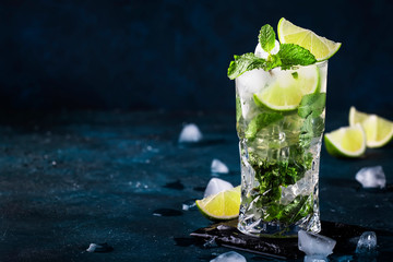 Mojito cocktail or mocktail with lime, mint, and ice in glass on blue background. Summer cold alcoholic non-alcoholic drink,  beverage and cocktail. Copy space