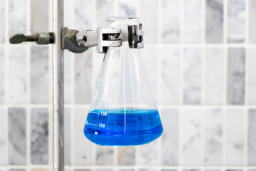 Erlenmeyer flask contain blue color solution on tile background