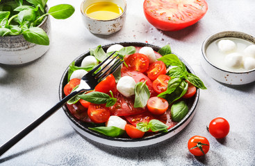 Tasty caprese salad with ripe red tomatoes and mozzarella cheese with fresh green basil leaves. Italian food. Top view