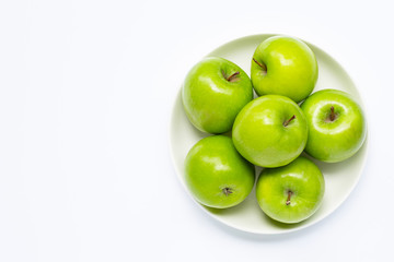 Fresh green apples on  white plate on white background.