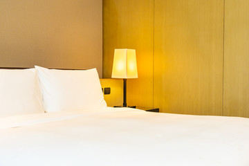 White comfortable pillow and blanket on bed with light lamp
