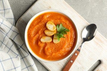 Composition with bowl of pumpkin puree with croutons on gray background, top view
