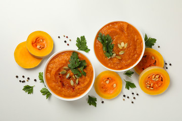 Composition with bowl of pumpkin soup on white background, top view