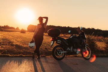 Female biker standing next to her bike, taking a break. Afternoon light
