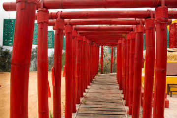 Fototapeta na wymiar Wooden red torii and Su Tong Pae bamboo bridge in Wat Phu Sa Ma temple in Ban Kung Mai Sak village at Pai city for thai people and foreign travelers travel visit in Mae Hong Son, Thailand