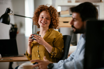 Colleagues in office. Businesswoman and businessman discussing work while drinking coffee.