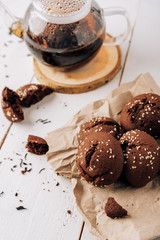 Teapot with black tea and homemade chocolate cookies on a white natural wooden background
