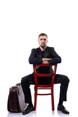 A bearded business man sits on a chair on a white background.
