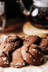 Teapot with black tea and homemade chocolate cookies on a brown natural wooden background