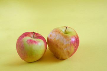 A whole Apple and a bitten Apple lie on a colored background