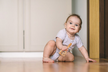 A nine-month-old baby crawls on the floor, looks at the camera with an interest and delight