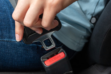 Close-up of a caucasian female hand holding a seat belt buckle for fastening in a car. Car safety concept