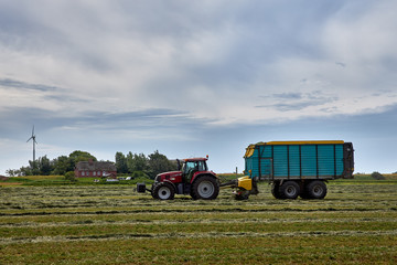 Bauer auf seinem Traktor bei der Heuernte, an einem sonnigen Tag
