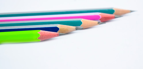 Fototapeta premium Five different colored wood pencil crayons placed beside one another on white background
