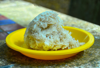 Cooked rice mixed muesli into a ball, place in a dish on a yellow table.