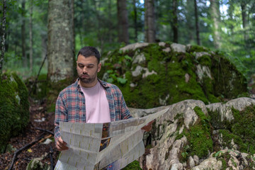 Traveler man with beard reading map in nature.