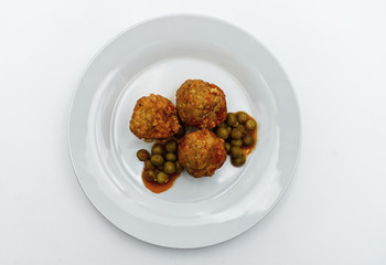 Meatballs with peas in white plate, isolated on white background. 