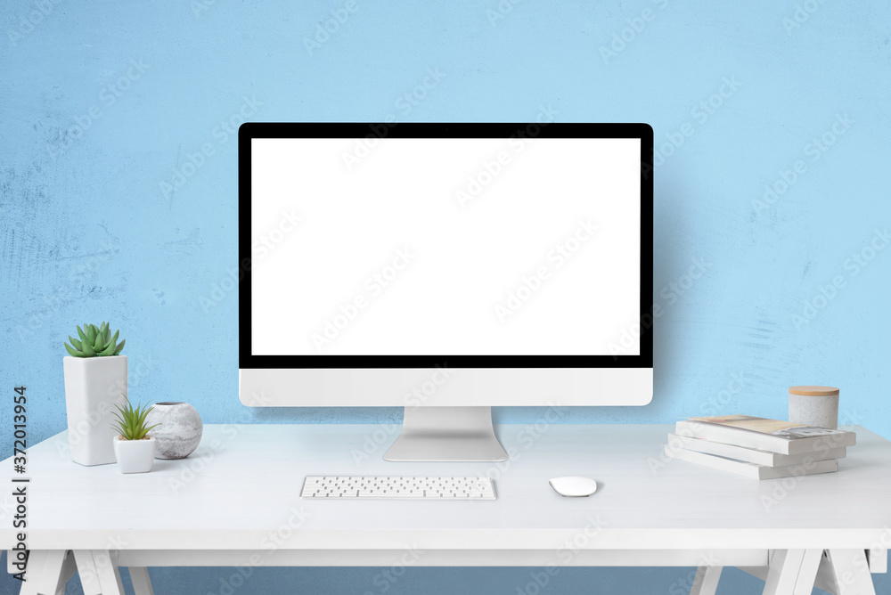 Poster Modern computer display mockup on work desk. Isolated screen for web site design promotion concept. Blue wall in background