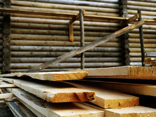 Construction of a wooden house. Planks near the wall as building material.