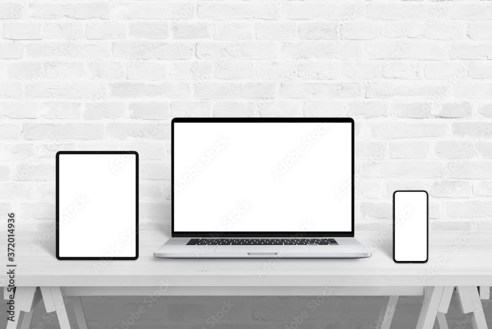 Poster Devices with isolated screens for responsive web design promotion. Web design studio concept on white wooden desk and brick wall in background