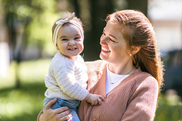 A young mother walks with a one-year-old baby, holds him in her arms, hugs. Communication with the...