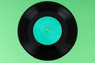 Old vinyl disc on green background. Old vintage vinyl record.
