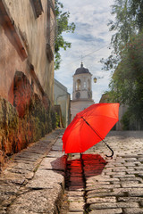 Red umbrella, clock tower and European narrow street