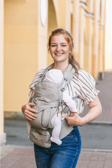 Active young mother with a 2-3 month old baby in a carrier. How to keep an active social life in a big city after the birth of a child