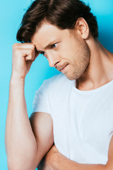 Pensive man in white t-shirt looking away on blue background