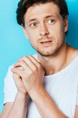 Obraz premium Frightened man in white t-shirt looking away on blue background