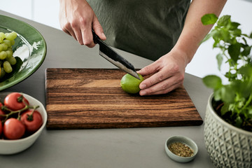 Mann, der eine Limette auf einem Holzbrett in Scheiben schneidet