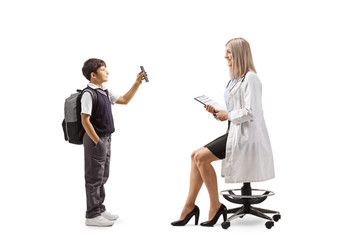 Full length profile shot of a schoolboy standing and showing a mobile phone to a female pediatrician doctor
