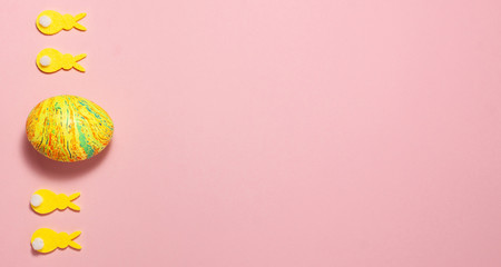 Yellow velvet bunnies and easter eggs on pink background on the left side with space for text. Flat lay top view. Easter concept