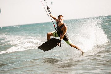 Kitesurfing. Man rides on kite on waves