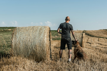 Man with Dog on Summer Meadow. Picturesque Countryside Landscape. Local Adventure and Social Distancing.