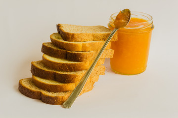 the genuine ingredients to start a healthy breakfast . 
 A scales of slices of bread leads to a jar of jam