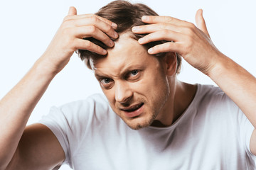 Dissatisfied man touching hair and looking at camera isolated on white
